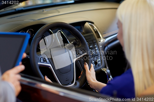 Image of woman and car dealer with tablet pc in auto salon