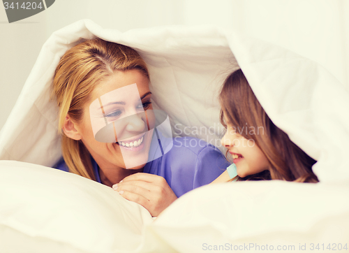 Image of mother and little girl under blanket at home