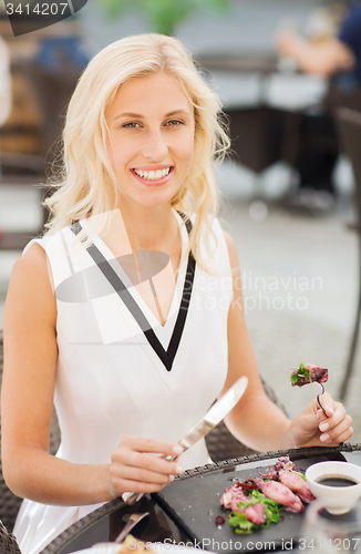 Image of happy woman eating dinner at restaurant terrace