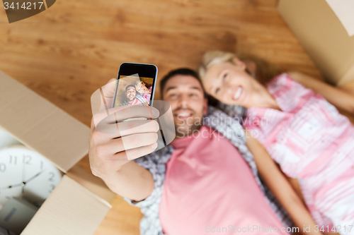 Image of couple taking selfie with smartphone on floor