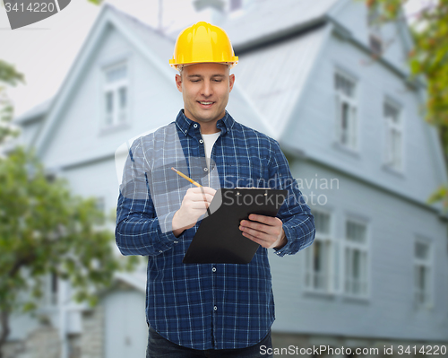 Image of smiling male builder in helmet with clipboard