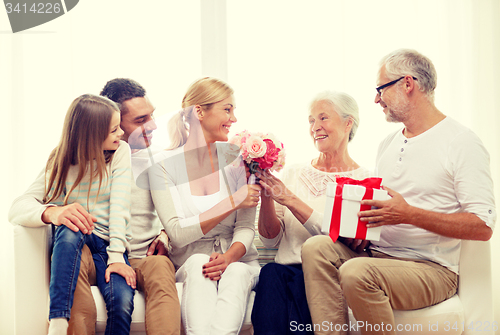 Image of happy family with bunch and gift box at home