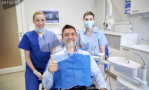 Image of happy female dentists with man patient at clinic