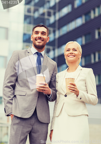 Image of smiling businessmen with paper cups outdoors