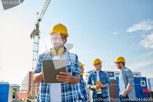 Image of builder in hardhat with tablet pc at construction