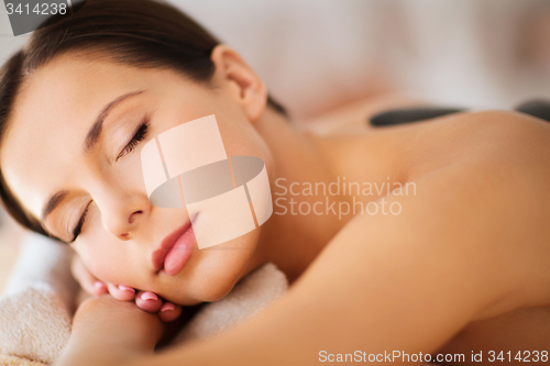 Image of beautiful woman in spa salon with hot stones