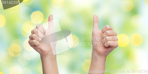 Image of woman hands showing thumbs up over blue sky