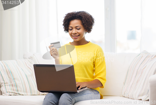 Image of happy african woman with laptop and credit card