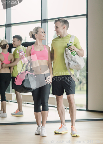 Image of smiling couple with water bottles in gym