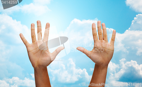 Image of two african hands making high five over blue sky