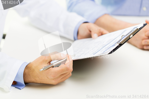 Image of close up of male doctor and patient with clipboard