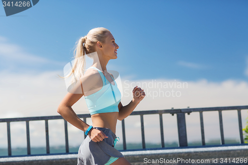 Image of smiling young woman running outdoors