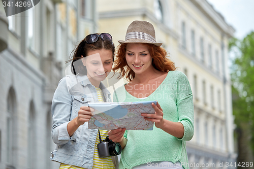 Image of smiling teenage girls with map and camera outdoors