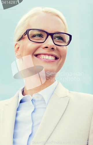 Image of young smiling businesswoman over office building
