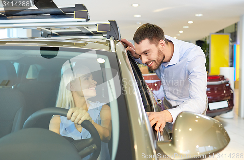 Image of happy couple buying car in auto show or salon