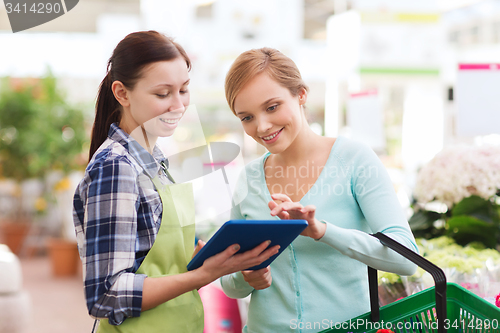 Image of happy women with tablet pc in greenhouse