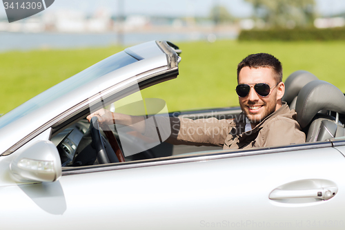 Image of happy man driving cabriolet car outdoors
