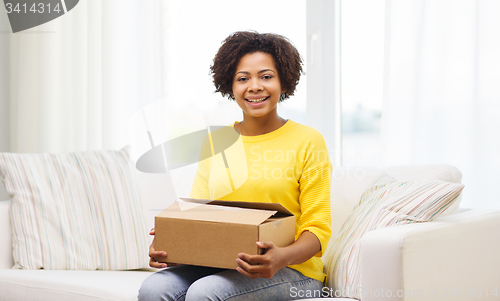 Image of happy african young woman with parcel box at home