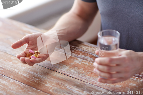 Image of close up of male hands holding pills and water