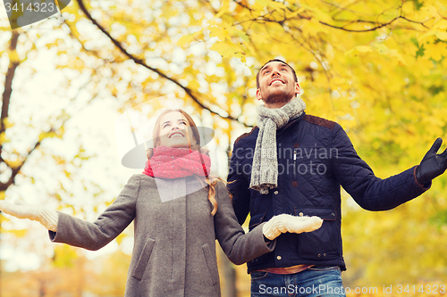 Image of smiling couple looking up in autumn park