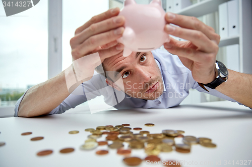 Image of businessman with piggy bank and coins at office