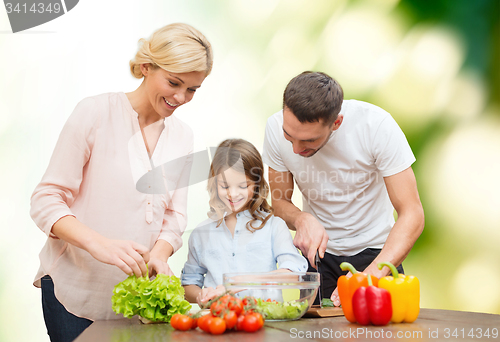 Image of happy family cooking vegetable salad for dinner