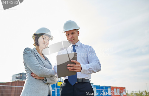 Image of happy builders in hardhats with tablet pc outdoors