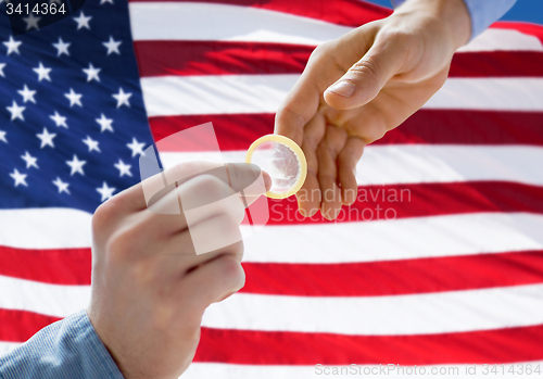 Image of close up of male gay couple hands giving condom