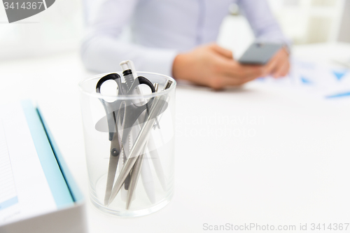 Image of close up of cup with scissors and pens at office