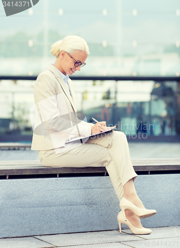 Image of young smiling businesswoman with notepad outdoors