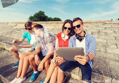 Image of group of smiling friends with tablet pc outdoors