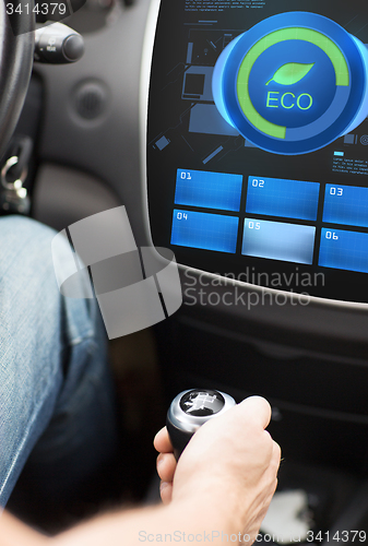 Image of hand with gearshift and car eco mode on screen