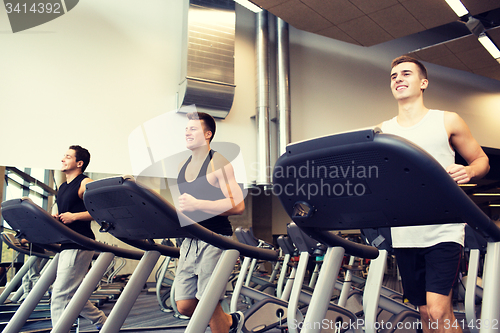 Image of smiling men exercising on treadmill in gym