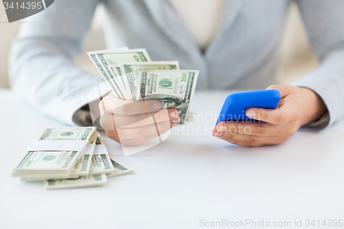 Image of close up of woman hands with smartphone and money