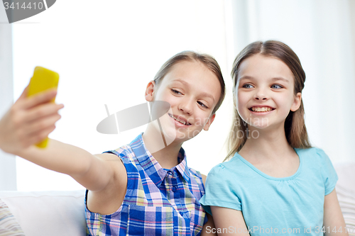 Image of happy girls with smartphone taking selfie at home