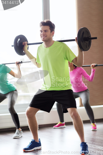 Image of group of people exercising with barbell in gym