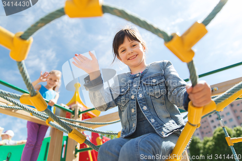 Image of happy little girl climbing on children playground