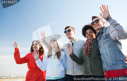 Image of happy teenage friends in shades waving hands