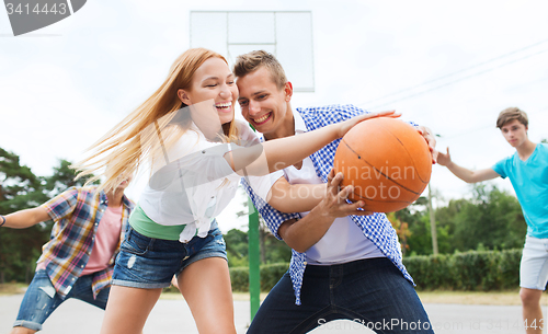 Image of group of happy teenagers playing basketball