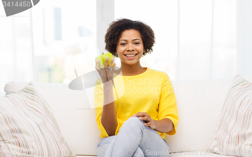 Image of happy african american woman with green apple