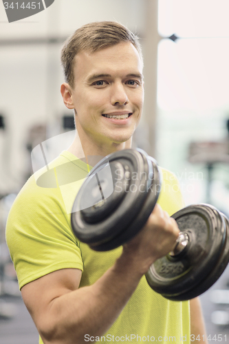 Image of smiling man with dumbbell in gym