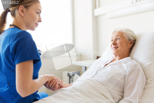Image of doctor or nurse visiting senior woman at hospital