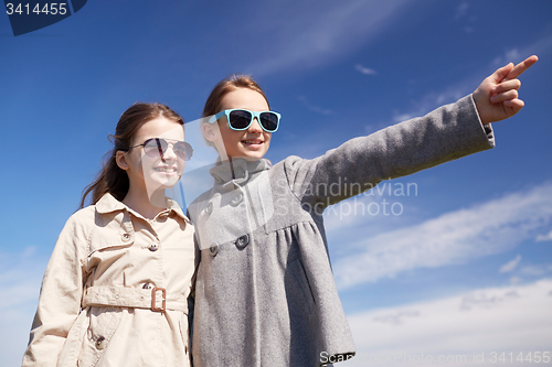 Image of happy little girls hugging and pointing finger