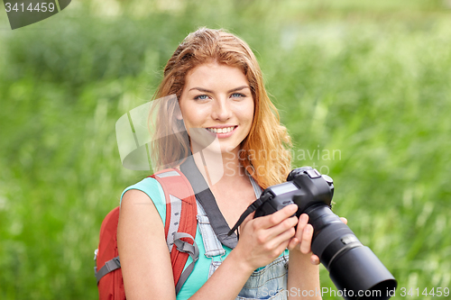 Image of happy woman with backpack and camera outdoors