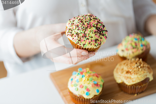 Image of close up of woman with glazed cupcakes or muffins