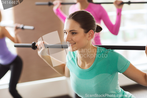 Image of group of people exercising with bars in gym