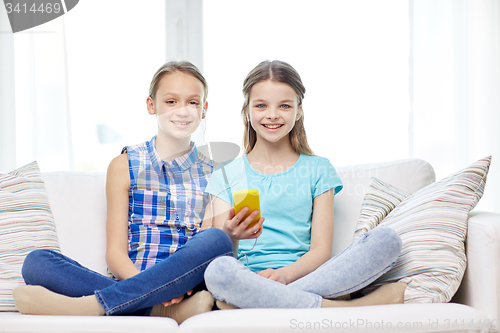 Image of happy girls with smartphone sitting on sofa