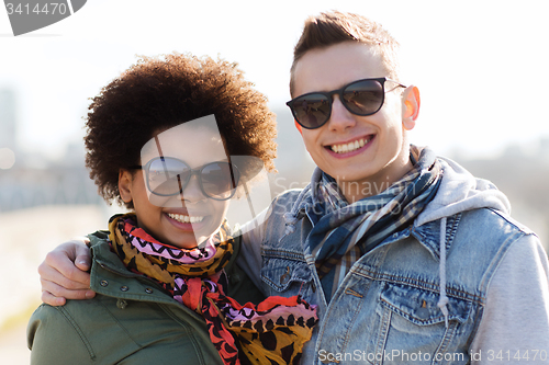 Image of happy teenage friends in shades hugging outdoors