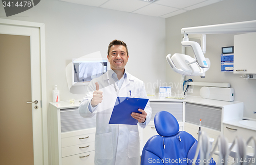 Image of happy male dentist showing thumbs up at clinic