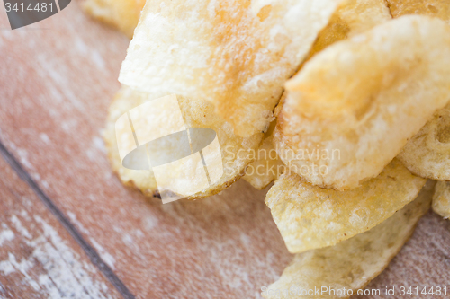 Image of close up of crunchy potato crisps on wooden table